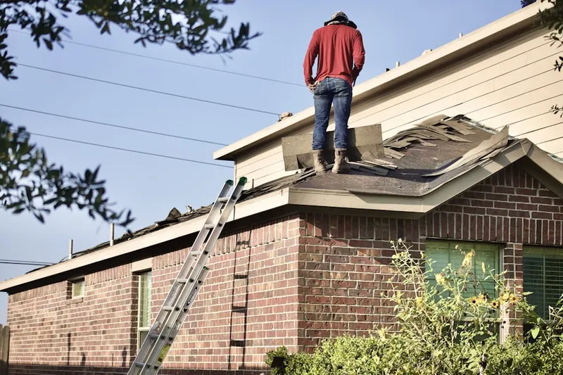 Professional roofer working on a residential roof in Ellis